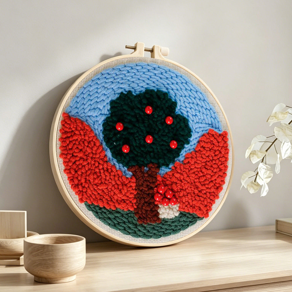 Colourful tree with red beads punch needle artwork displayed on a table
