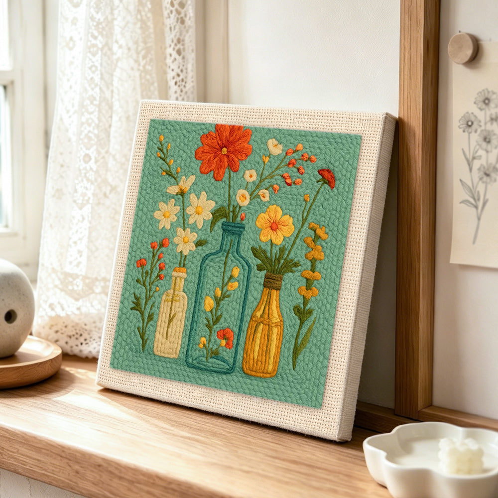 Colourful wildflowers in the glass bottles punch needle artwork displayed on a table