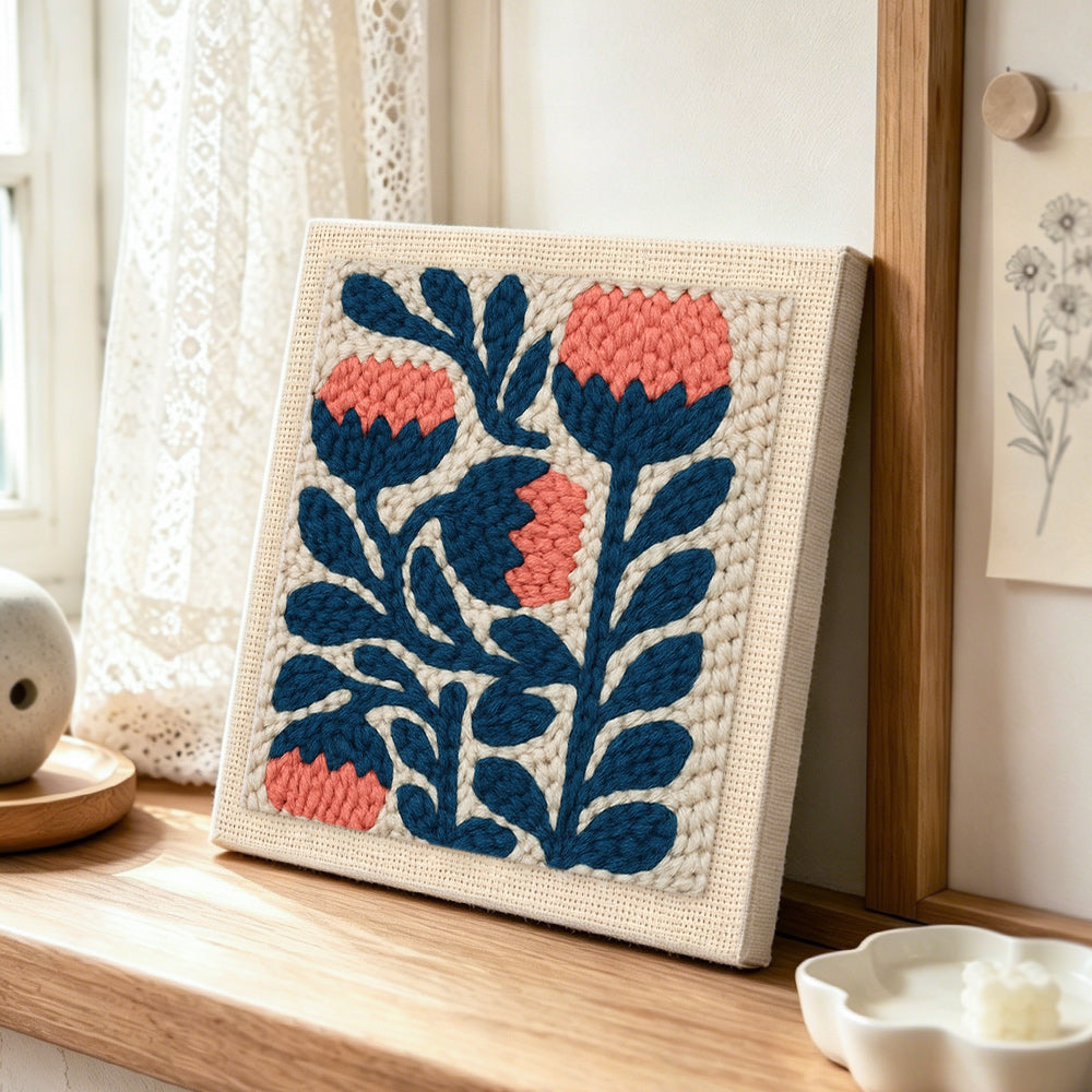 Coral and navy flowers punch needle artwork displayed on a table