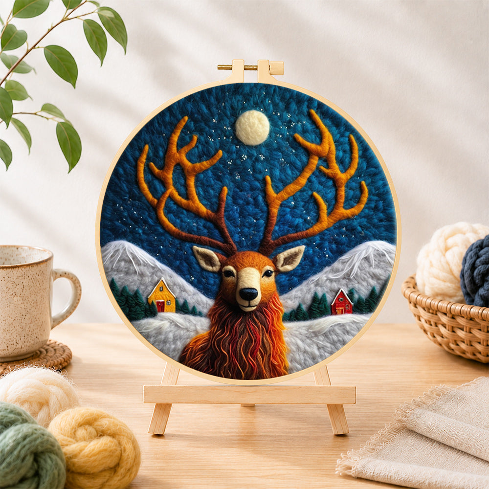 Finished cosy winter cabin and stag needle felting displayed on a wooden easel