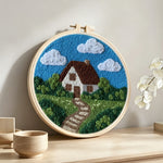 Countryside cottage with pathway punch needle artwork displayed on a table