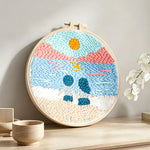 Couple on beach at sunset punch needle artwork displayed on a table