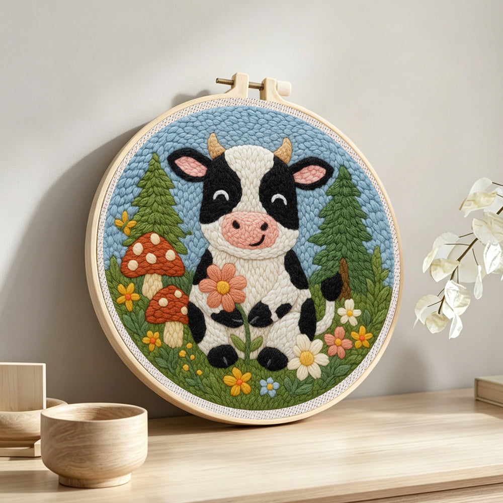 Cow in the meadow and flower forest punch needle artwork displayed on a table
