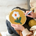 Creating handmade cream flower on mustard yellow punch needle artwork