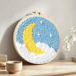 Crescent moon and stars punch needle artwork displayed on a table