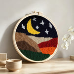 Crescent moon and white stars above the colourful mountains punch needle artwork displayed on a table