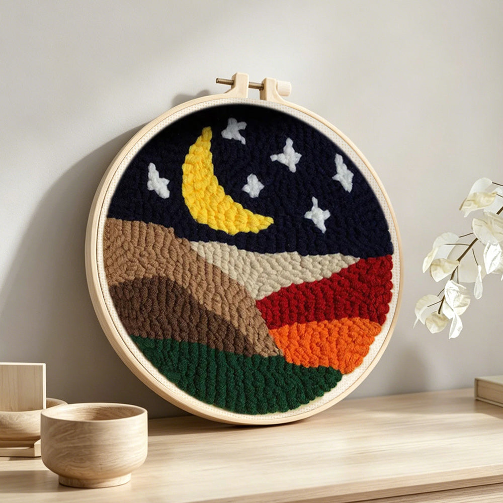 Crescent moon and white stars above the colourful mountains punch needle artwork displayed on a table