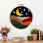 Finished crescent moon and white stars above the colourful mountains artwork displayed on a wall