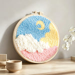 Crescent moon over colourful clouds punch needle artwork displayed on a table