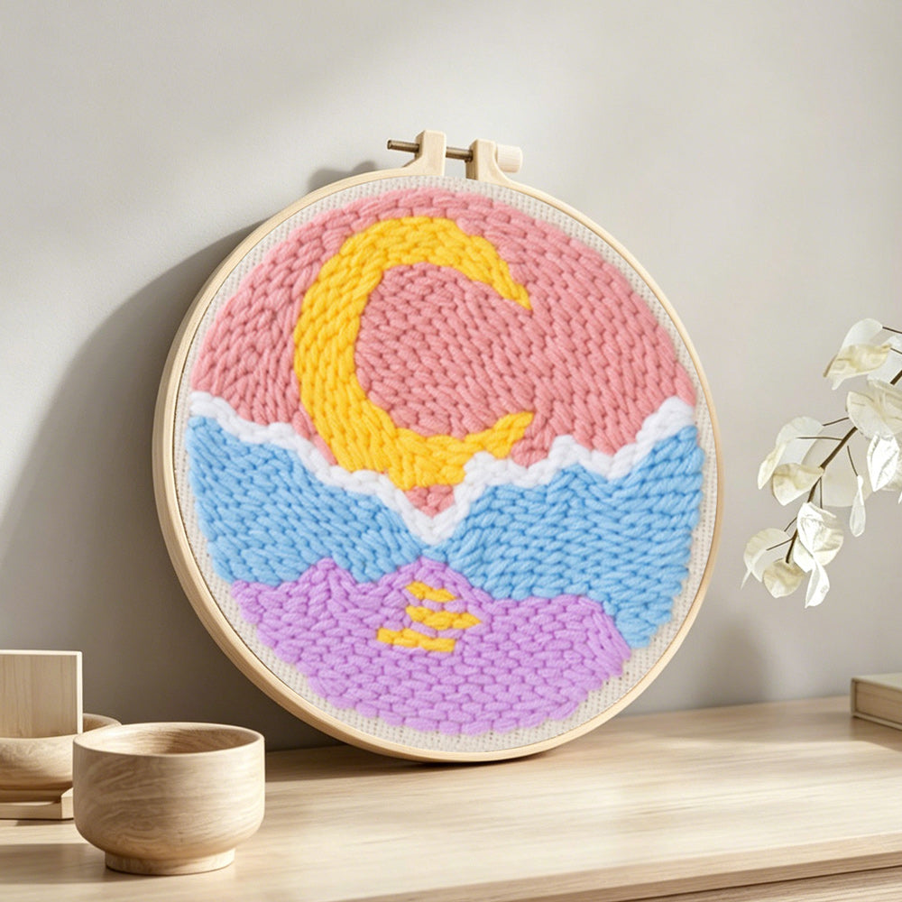 Crescent moon over mountain and sea punch needle artwork displayed on a table