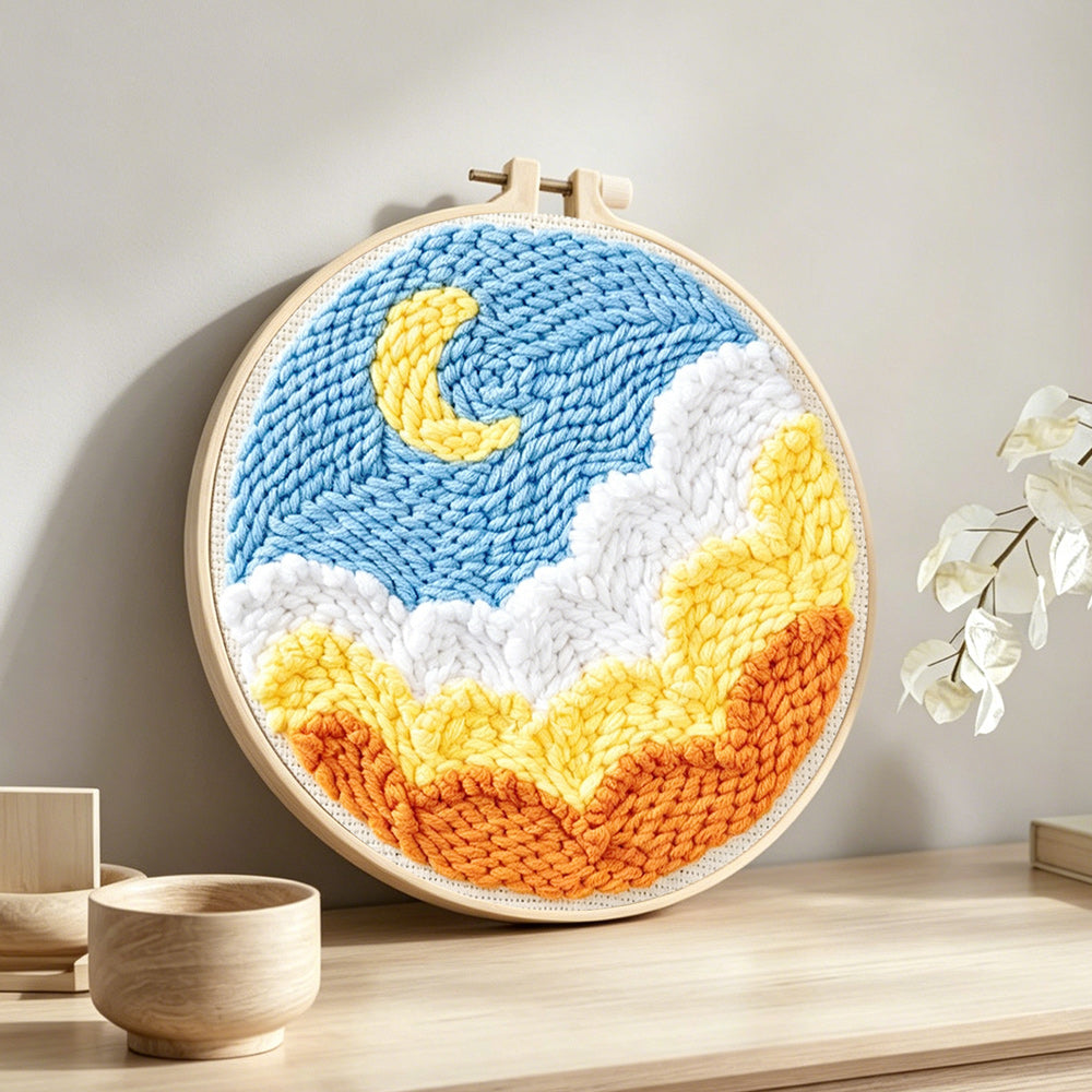 Crescent moon over ocean waves punch needle artwork displayed on a table