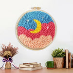 Finished crescent moon over pink and blue cloud sky artwork displayed on a wall