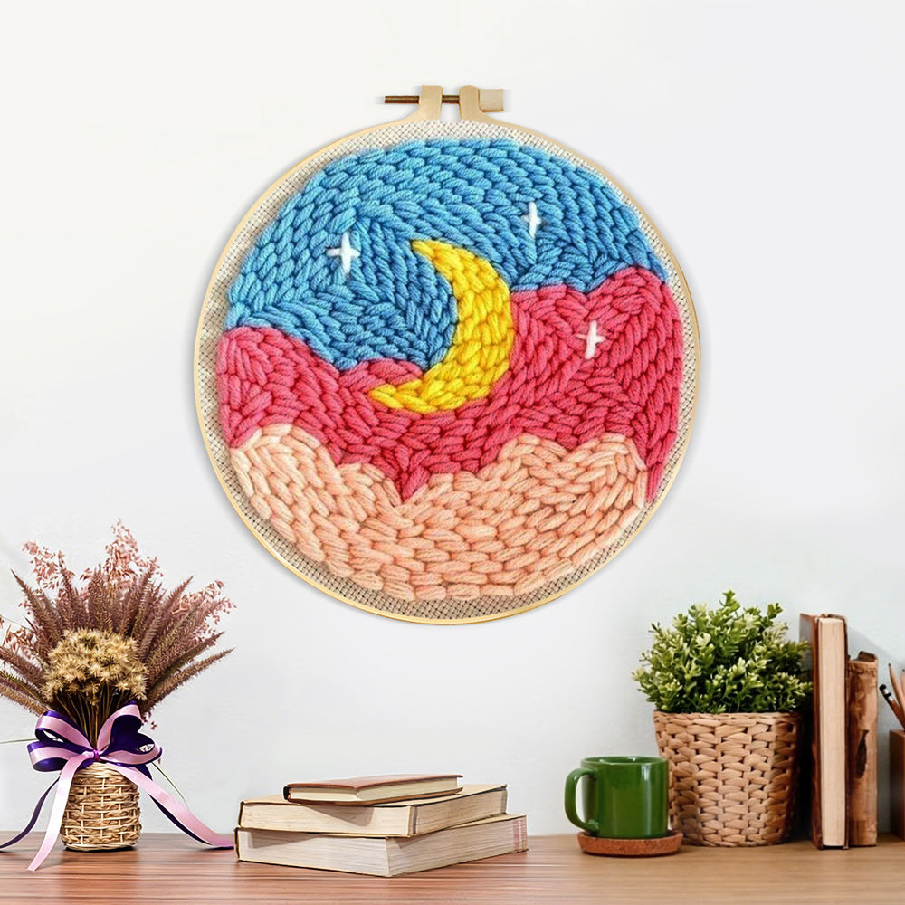 Finished crescent moon over pink and blue cloud sky artwork displayed on a wall