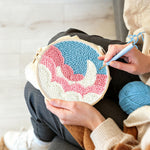 Creating handmade crescent moon over pink and white clouds punch needle artwork