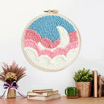 Finished crescent moon over pink and white clouds artwork displayed on a wall