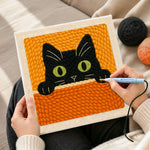Creating handmade curious black cat peeking over punch needle artwork