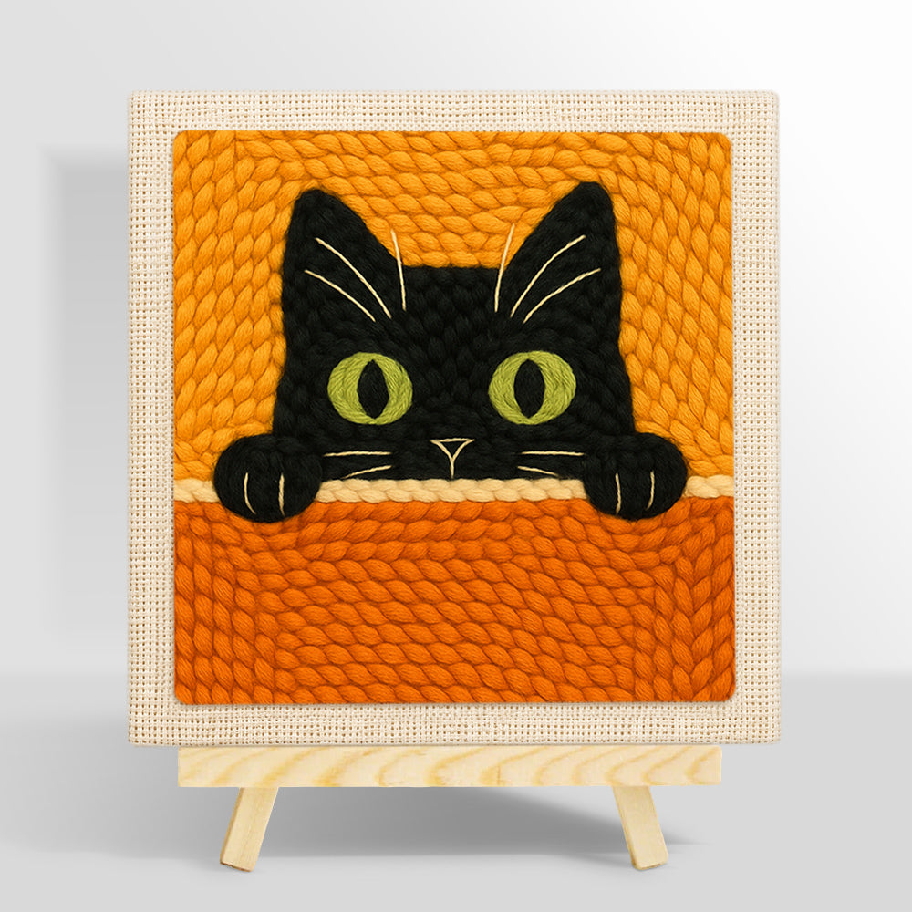 Curious black cat peeking over punch needle kit for beginners