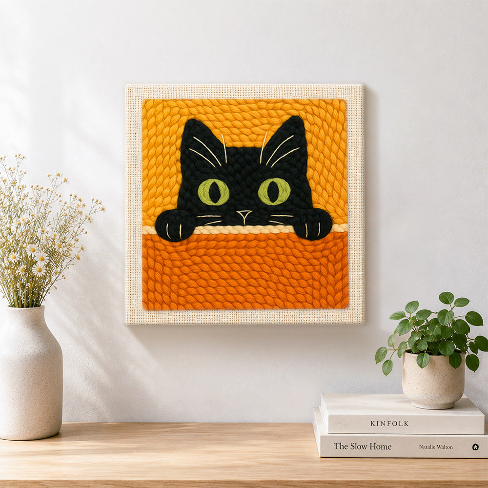 Finished curious black cat peeking over artwork displayed on a wall