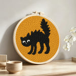 Curled black cat punch needle artwork displayed on a table
