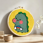 Cute baby dinosaur punch needle artwork displayed on a table