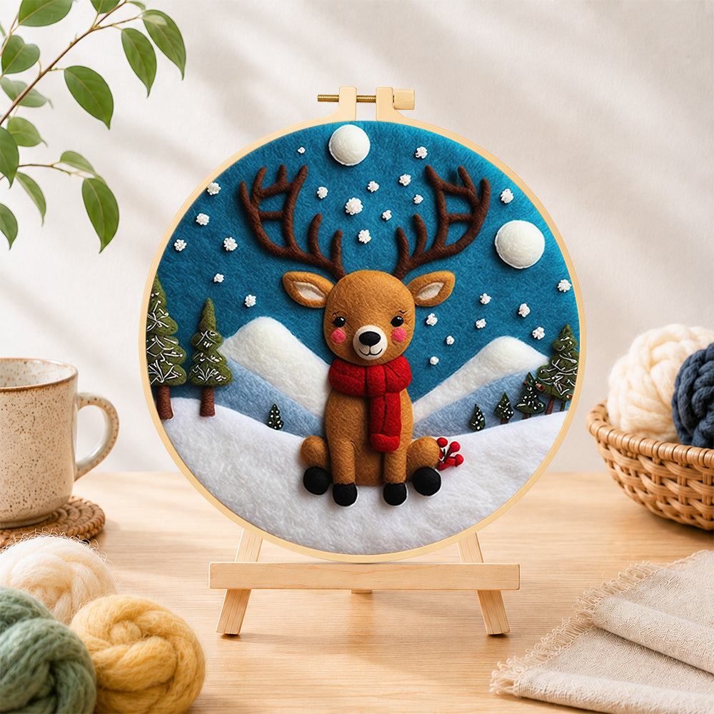 Finished cute baby reindeer sitting in the snow needle felting displayed on a wooden easel