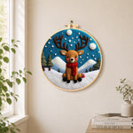 Cute baby reindeer sitting in the snow needle felt wall art displayed in a bright home interior
