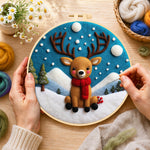 Creating the cute baby reindeer sitting in the snow wool painting by hand with a felting needle