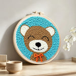 Cute bear with orange bow tie punch needle artwork displayed on a table