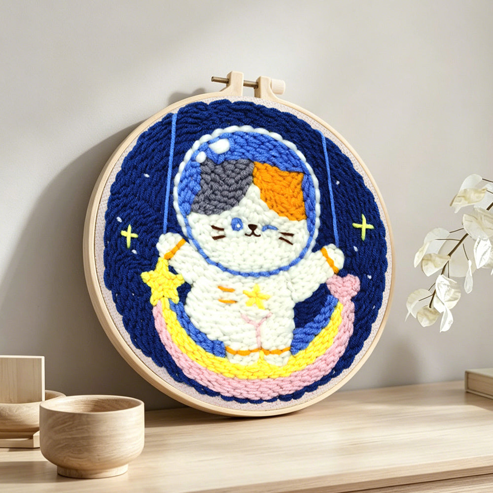 Cute calico cat astronaut on rainbow moon punch needle artwork displayed on a table