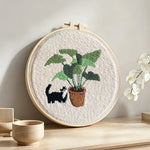 Cute cat by houseplant punch needle artwork displayed on a table