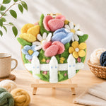 Finished cute flower bed with white picket fence needle felting displayed on a wooden easel