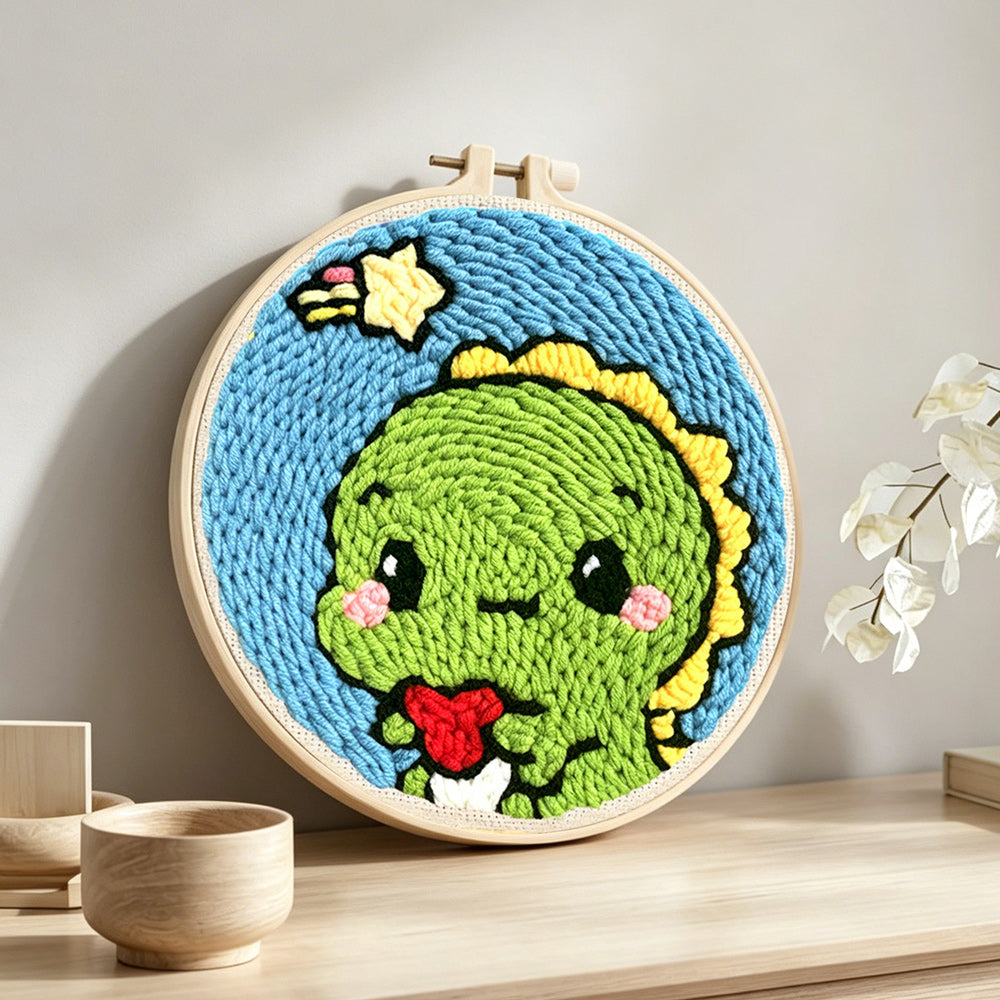 Cute green baby dinosaur punch needle artwork displayed on a table
