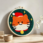 Cute orange cat in santa hat punch needle artwork displayed on a table