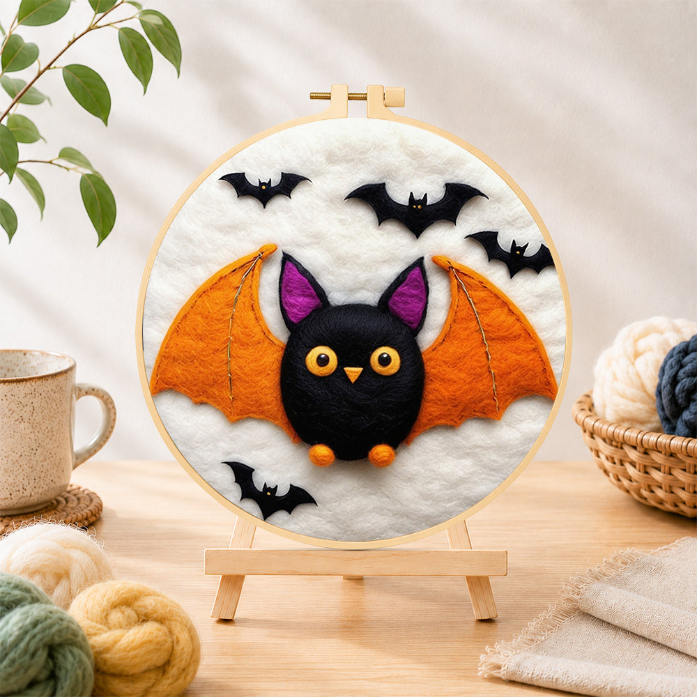 Finished cute orange-winged bat needle felting displayed on a wooden easel