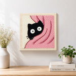 Finished cute peeking kitten in pink blanket artwork displayed on a wall