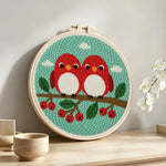 Cute red birds on berry branch punch needle artwork displayed on a table