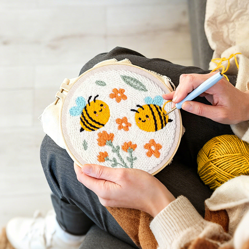 Creating handmade cute smiling bumblebees and orange flowers punch needle artwork