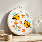 Cute smiling bumblebees and orange flowers punch needle artwork displayed on a table