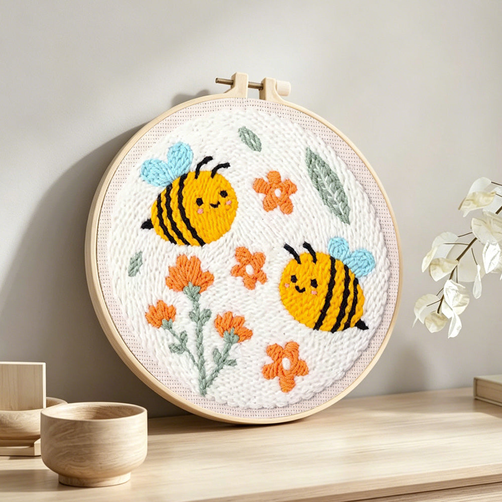 Cute smiling bumblebees and orange flowers punch needle artwork displayed on a table