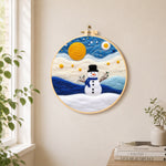 Cute snowman under the full moon needle felt wall art displayed in a bright home interior