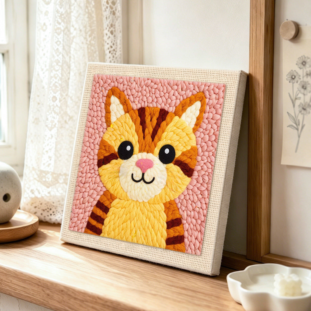 Cute striped kitten with pink nose punch needle artwork displayed on a table