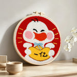 Cute white duck holding lucky gold bag punch needle artwork displayed on a table