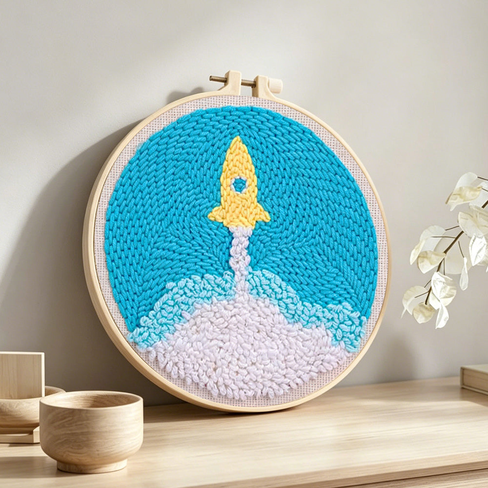 Cute yellow rocket launch punch needle artwork displayed on a table