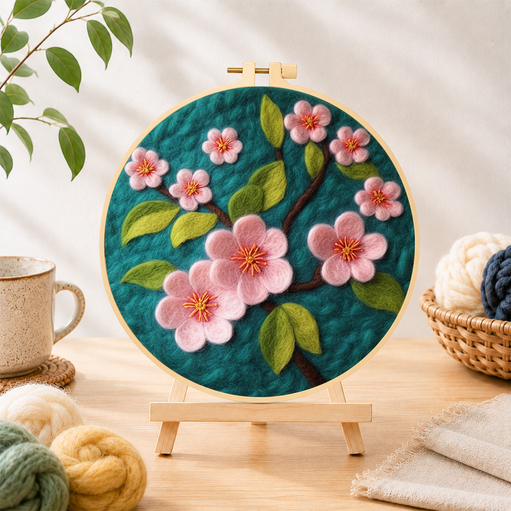 Finished delicate pink flowers on dark green needle felting displayed on a wooden easel