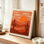 Desert sunset and cacti punch needle artwork displayed on a table