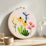 Dragonfly and garden wildflowers punch needle artwork displayed on a table