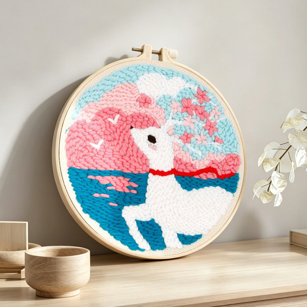 Dreamy clouds, sea, and white deer punch needle artwork displayed on a table