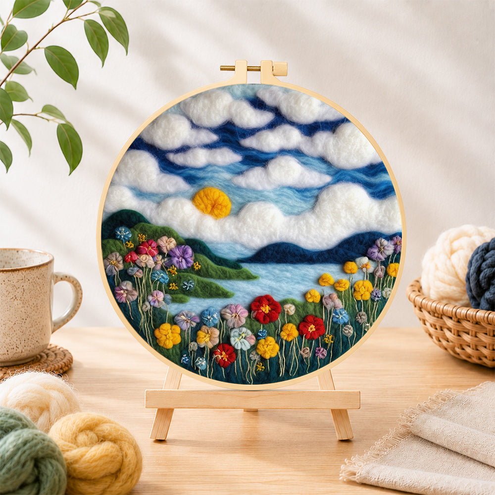 Finished dreamy cloudscape and flower meadow needle felting displayed on a wooden easel