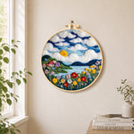 Dreamy cloudscape and flower meadow needle felt wall art displayed in a bright home interior