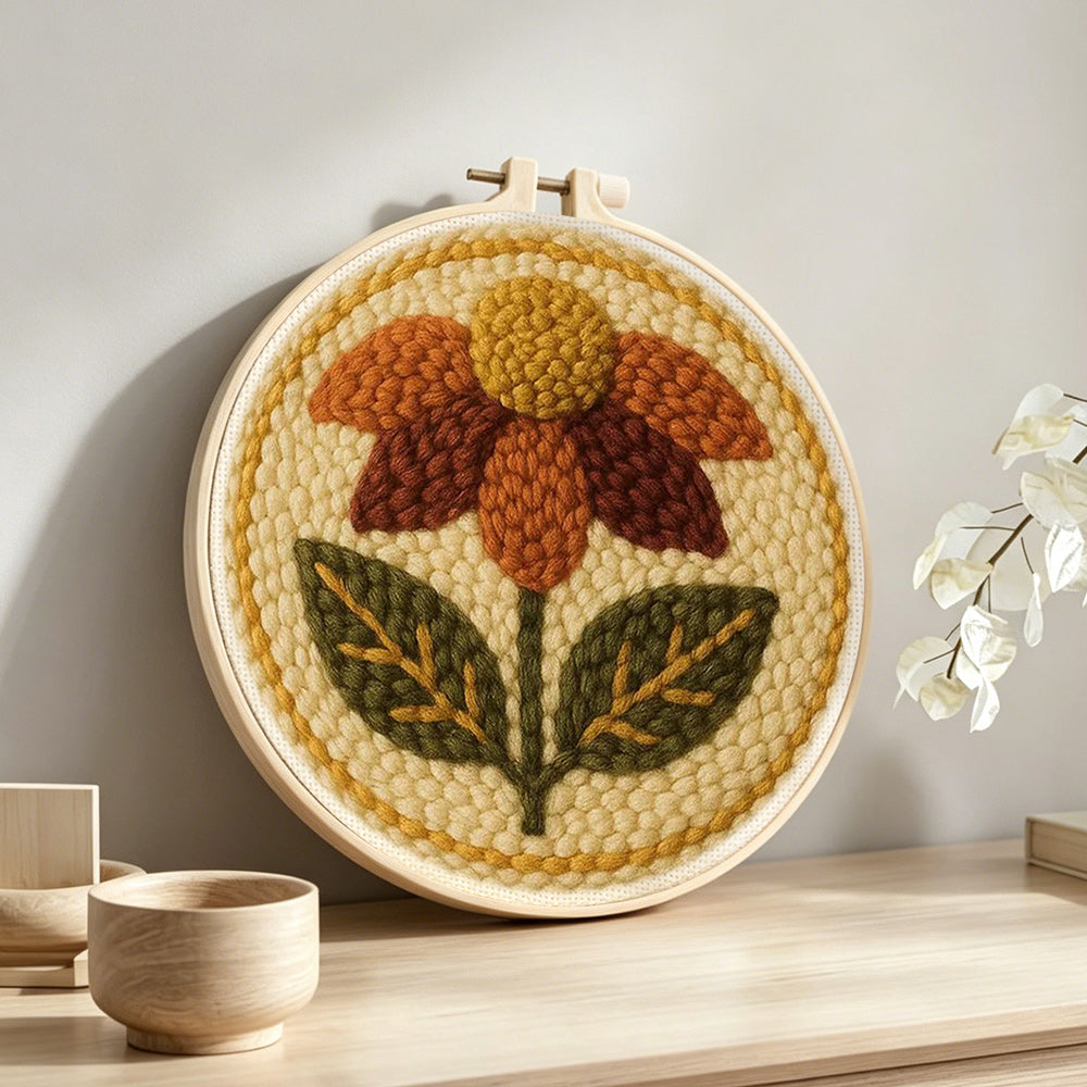 Earth tone autumn flower punch needle artwork displayed on a table
